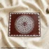 Handmade Aipan mandala artwork on red background featuring traditional Kumaoni folk design with intricate white patterns on canvas cloth